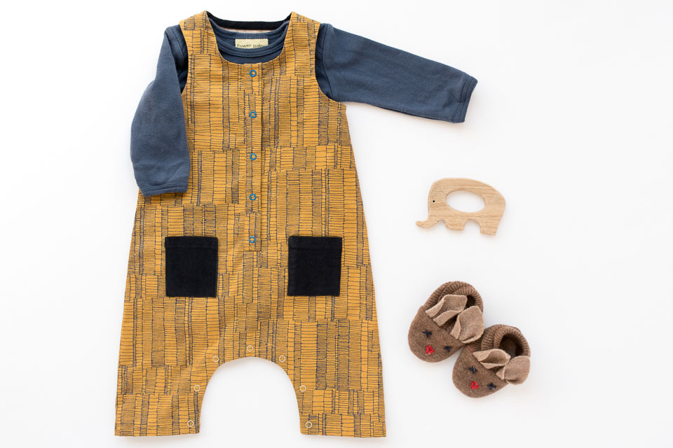 A Rain Dance Romper baby gift. A sleeveless romper with a front placket, bias bound armholes and neckhole, and crotch snaps for easy changing.