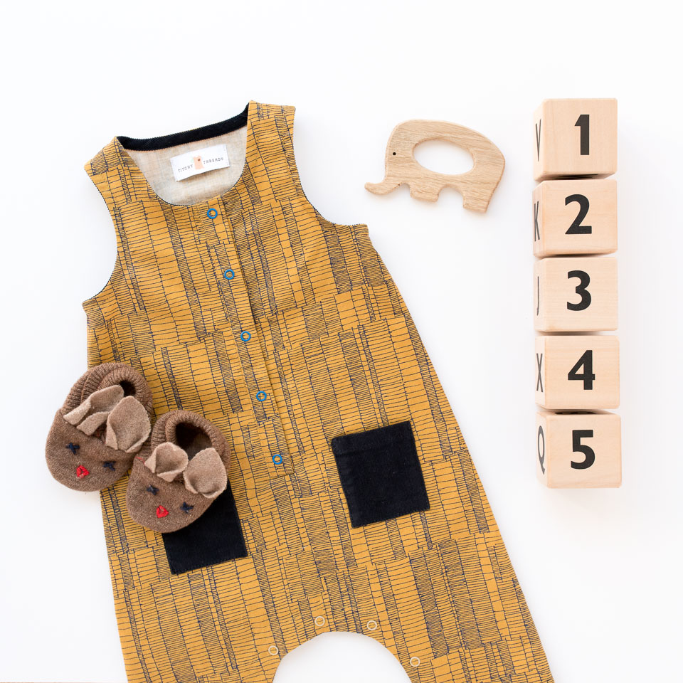 A Rain Dance Romper baby gift. A sleeveless romper with a front placket, bias bound armholes and neckhole, and crotch snaps for easy changing.